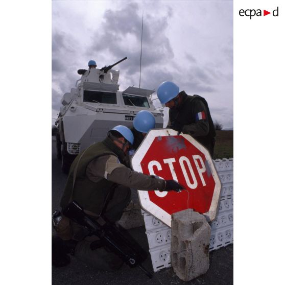 Des casques bleus du régiment d'infanterie chars de marine (RICM) fixent un panneau STOP à un poste de contrôle routier de véhicules civils près de Gracac.