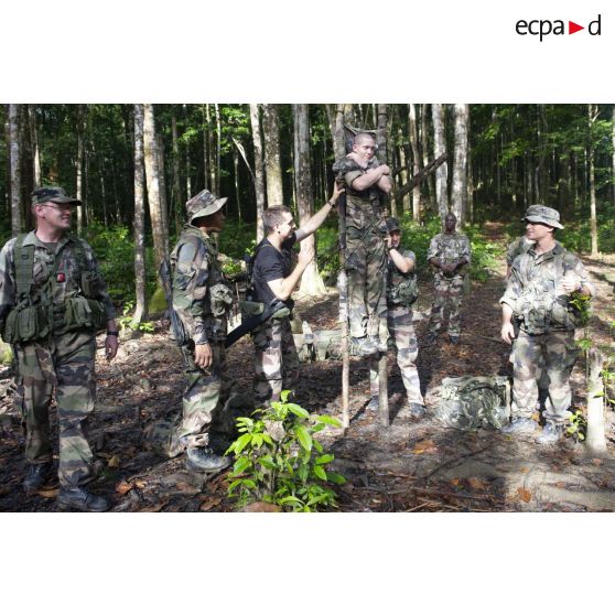 Des instructeurs du 9e régiment d'infanterie de marine (9e RIMa) montrent comment transporter un blessé sur un brancard de fortune à des stagiaires sur la zone d'instruction de Tuff, en Guyane française.