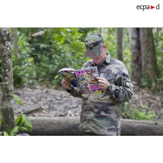 Un instructeur du 9e régiment d'infanterie de marine (9e RIMa) feuillette un magazine people sur la zone d'instruction de Tuff, en Guyane française.