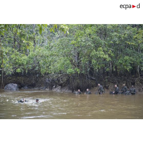 Des stagiaires apprennent à traverser une crique avec sac et armement sur la zone d'instruction de Tuff, en Guyane française.