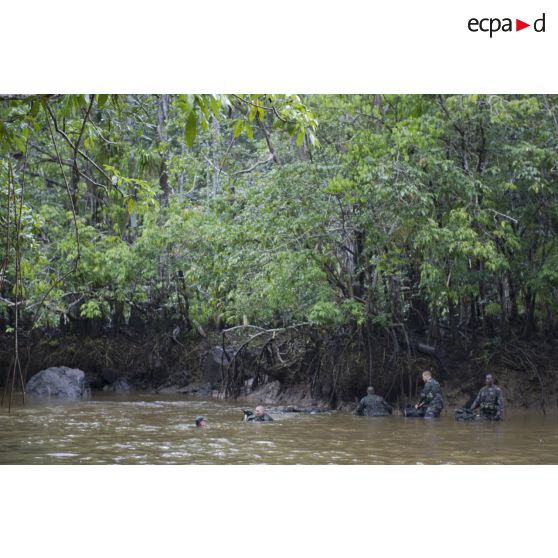 Des stagiaires apprennent à traverser une crique avec sac et armement sur la zone d'instruction de Tuff, en Guyane française.