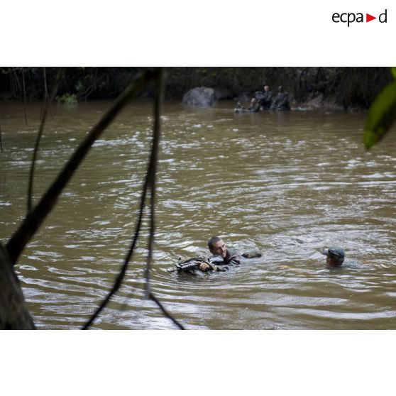 Des stagiaires apprennent à traverser une crique avec sac et armement sur la zone d'instruction de Tuff, en Guyane française.