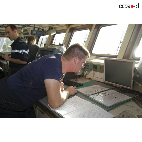 Un officier marinier consulte la carte maritime sur un ordinateur en passerelle de La Gracieuse, en Guyane française.