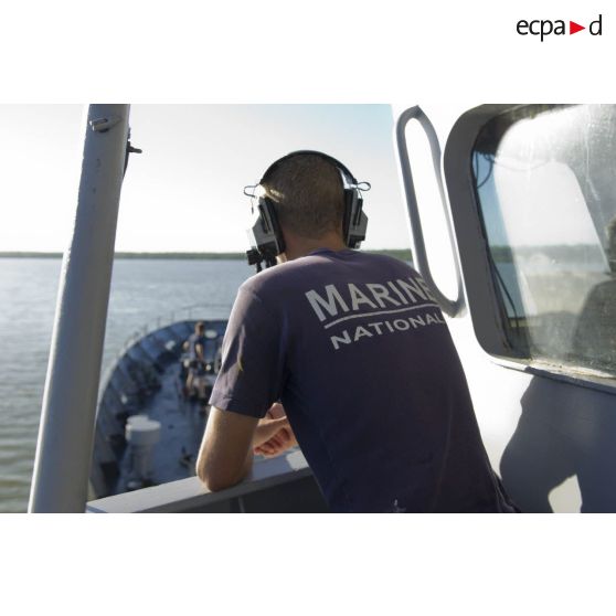 Un membre d'équipage surveille la manoeuvre d'appareillage du navire à bâbord de la passerelle de La Gracieuse, en Guyane française.