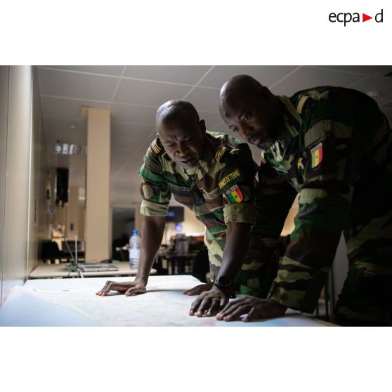 Des officiers sénégalais étudient les cartes au centre opérationnel du porte-hélicoptères amphibie (PHA) Tonnerre (L9014) à N'Gazobil, au Sénégal