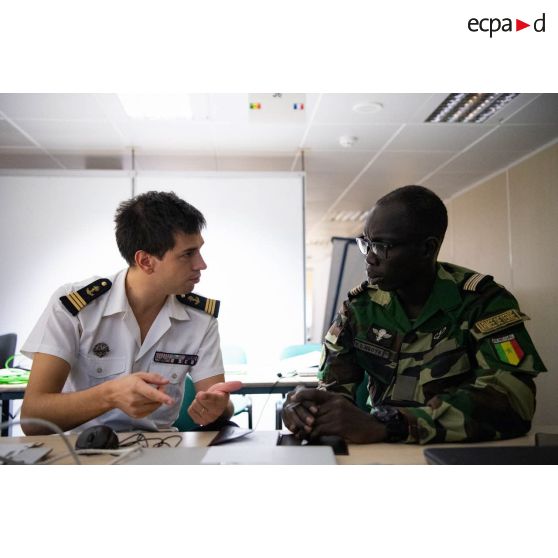 Le chef de bataillon Mamadou Diagne Ndoye travaille avec un lieutenant de vaisseau au centre opérationnel du porte-hélicoptères amphibie (PHA) Tonnerre (L9014) à N'Gazobil, au Sénégal