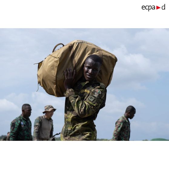 Un soldat ivoirien du 1er bataillon de commandos et de parachutistes (BCP) porte son parachute à son arrivée sur la zone de saut d'Assinie, en Côte d'Ivoire.