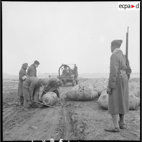 Transport de bombes par des prisonniers de guerre allemands sous l'oeil vigilant d'un tirailleur sénégalais.