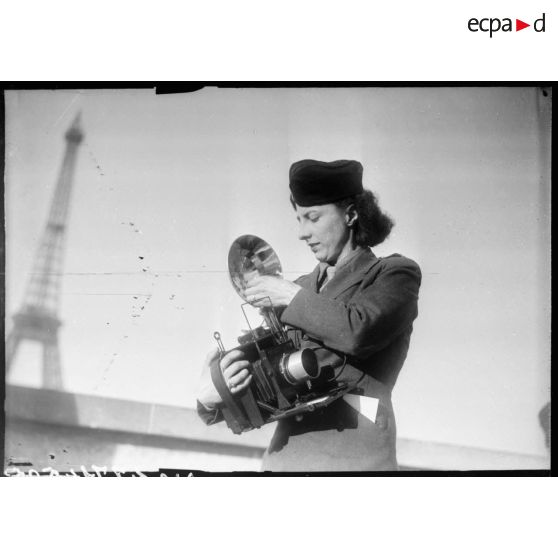 Une photographe des forces féminines de l'Air équipée d'un appareil Speed Graphic.