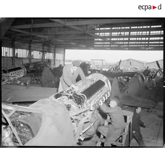 Mise en place des bougies du moteur d'un Curtiss sur la chaîne de montage.