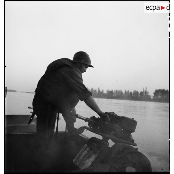 Un propulsiste du génie manoeuvre le moteur hors-bord d'un bateau d'assaut M2 sur le Rhin.