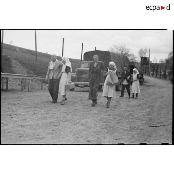 Des déportés du camp de Vaihingen libéré sont soutenus par des infirmières jusqu'aux tentes sous lesquelles un bataillon médical va leur prodiguer les premiers soins.