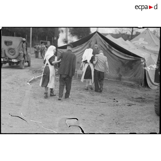 Des déportés du camp de Vaihingen libéré sont soutenus par des infirmières jusqu'aux tentes sous lesquelles un bataillon médical va leur prodiguer les premiers soins.