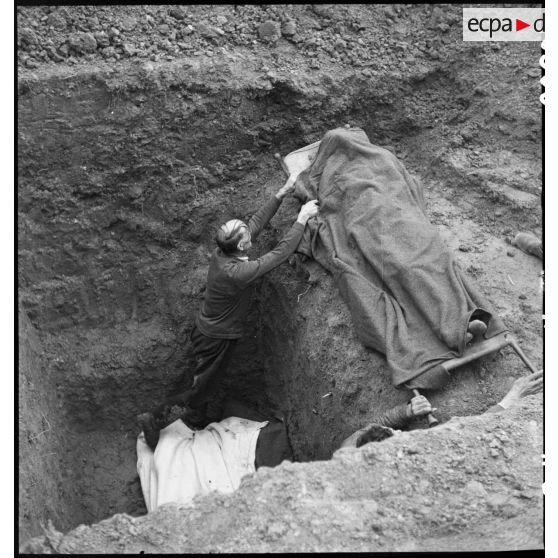 Des civils allemands déposent des dépouilles de déportés dans une fosse commune du camp de Vaihingen récemment libéré.