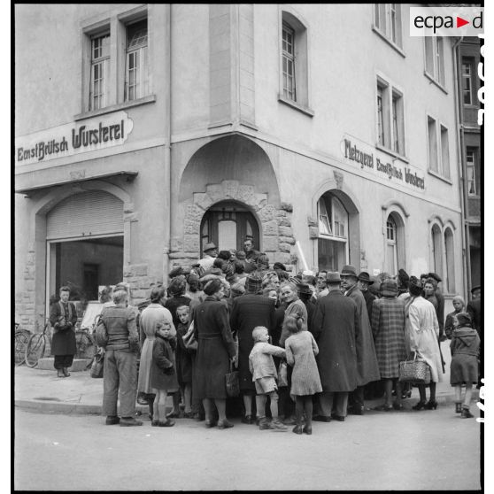 Population rassemblée devant un commerce dans une commune à proximité de Fützen.