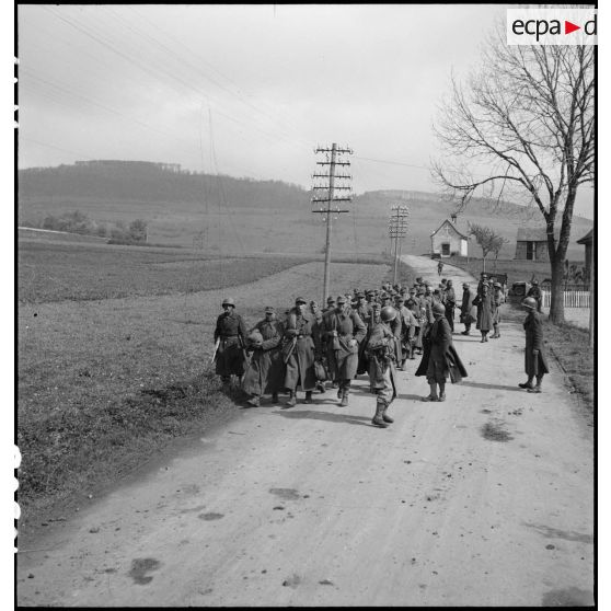 Des prisonniers de guerre allemands, encadrés par des soldats du combat command n°3 (CC3), sont emmenés vers des zones de rassemblement. A l'arière-plan, la chapelle Antoine à Fützen.