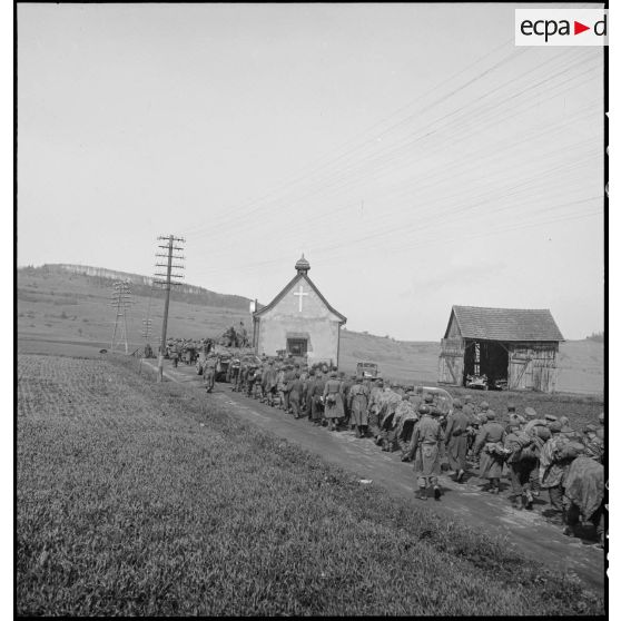 Des prisonniers de guerre allemands, encadrés par des soldats du combat command n°3 (CC3), passent à hauteur de la chapelle Antoine à Fützen.