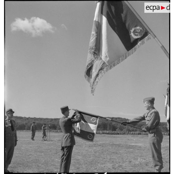 Le général de corps d'armée Leclerc décore l'étendard du 1er régiment de marche de spahis marocains (1er RMSM) lors de la cérémonie d'adieu à la 2e division blindée (2e DB).