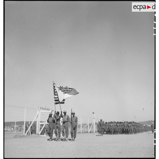 Défilé quotidien des troupes sur le camp d'entraînement disciplinaire américain des Milles, drapeau des Etats-Unis et du DTC en tête.