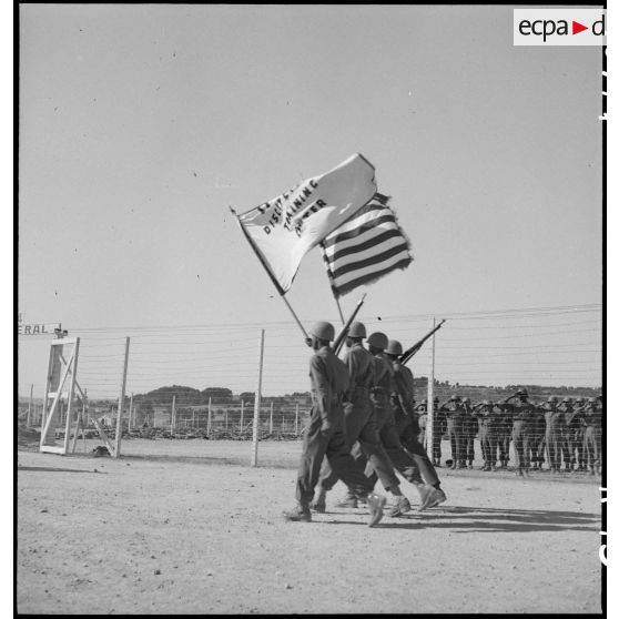 Défilé quotidien des troupes sur le camp d'entraînement disciplinaire américain des Milles, drapeau des Etats-Unis et du DTC en tête.