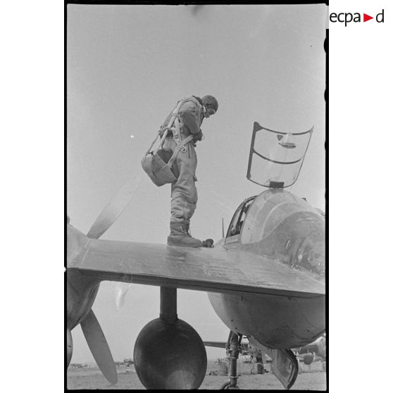 Le pilote ajuste son parachute avant de monter dans le cockpit de son avion.