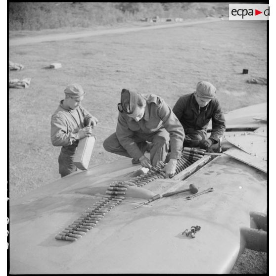 Des mécaniciens du groupe de chasse II/7 Nice approvisionnent en munitions une des mitrailleuses d'aile d'un Spitfire Mk V après un retour de mission.