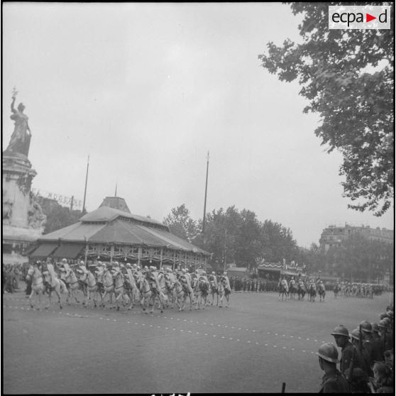 Place de la République. Défilé d'une fanfare de spahis. En arrière-plan, le Monument à la République de Léopold et François-Charles Morice, un manège et la tribune officielle.