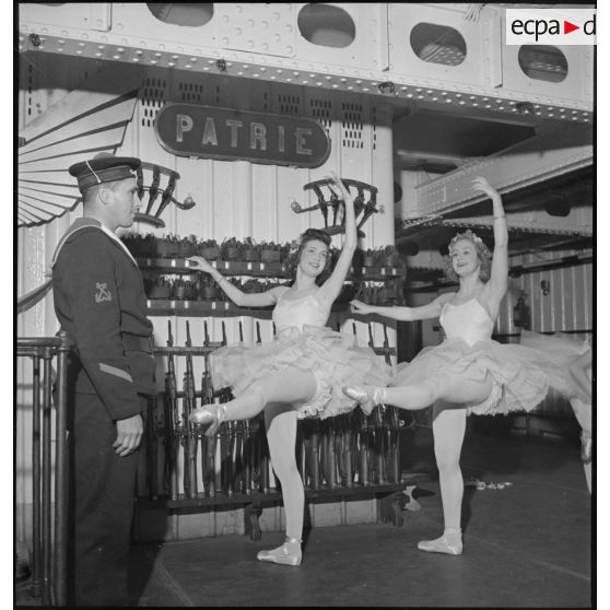 Des danseuses d'un corps de ballet font des exercices "à la barre" dans l'armurerie du porte-avions Béarn à bord duquel elles participent à un spectacle pour la soirée, la veille de Noël.