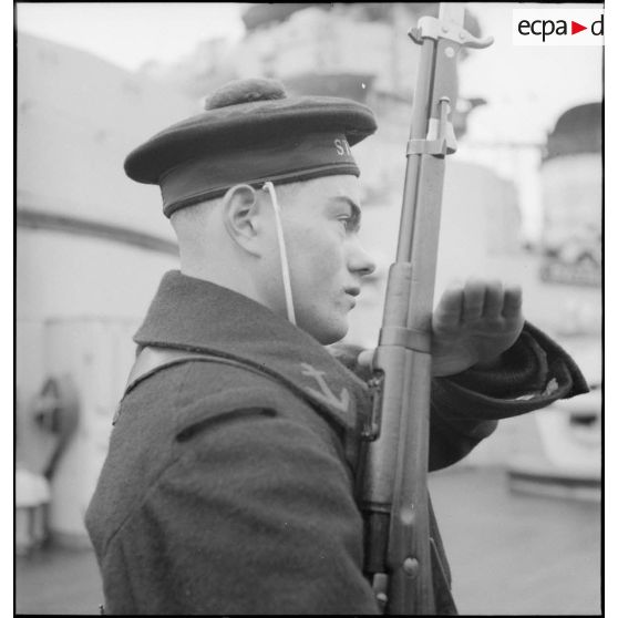 Portrait d'un marin présentant les armes à bord du cuirassé Strasbourg.