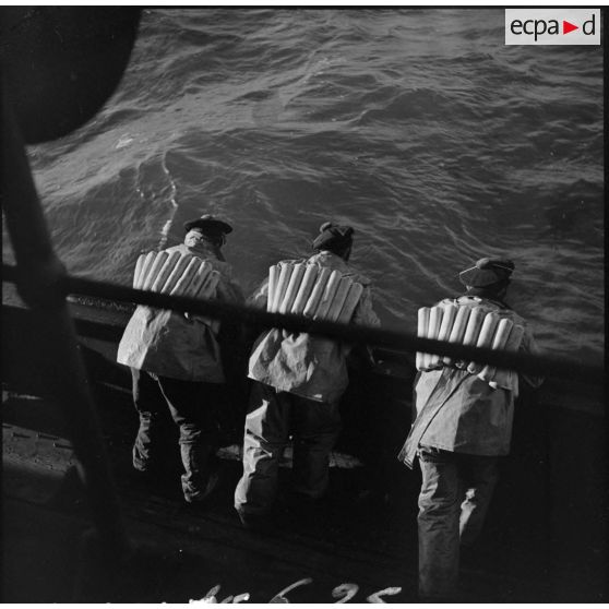 Marins accoudés au bastingage d'un chalutier armé par la Marine nationale.