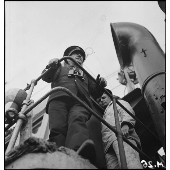 Portrait en pied et en contre-plongée du premier maître, commandant le chalutier de la marine marchande Roche noire, réquisitionné et armé par la Marine nationale.