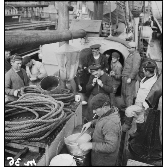 Membres d'équipage sur la plage avant du chalutier de la marine marchande Roche noire, réquisitionné et armé par la Marine nationale.