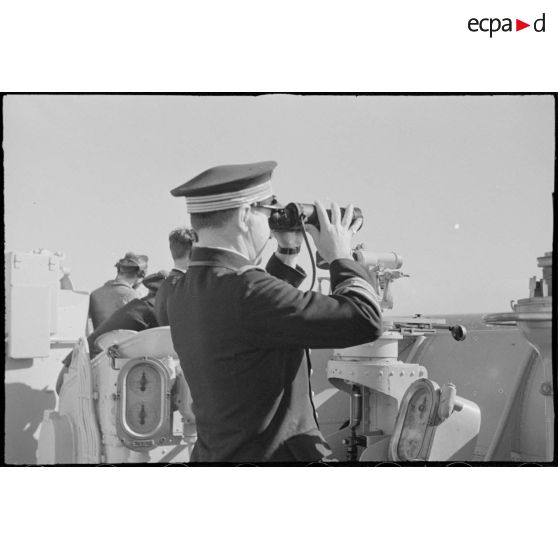 Le capitaine de vaisseau Yves Hamon, commandant le croiseur la Marseillaise, observe l'horizon aux jumelles.