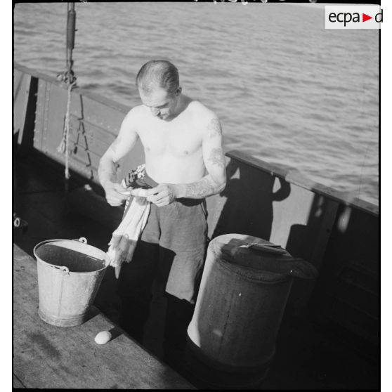 Un marin se rase sur le pont d'un chalutier réquisitionné par la Marine nationale comme dragueur de mines.