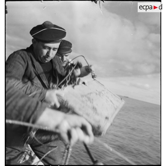 Mise à l'eau du triangle de drague à bord d'un chalutier réquisitionné et armé par la Marine nationale pour servir de dragueur de mines.