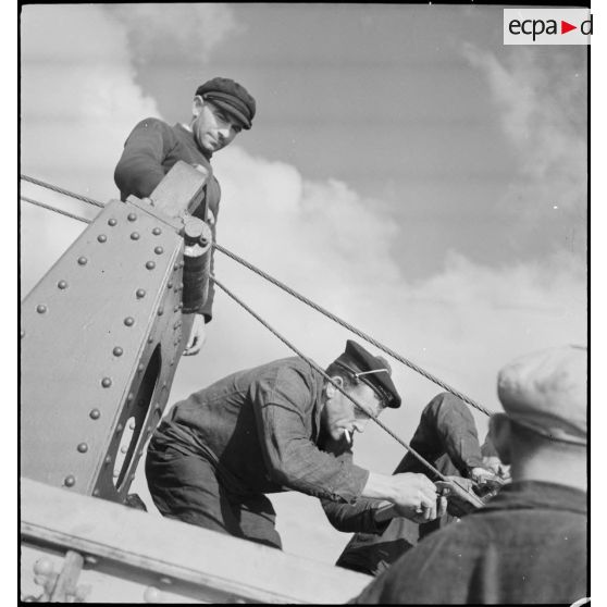 Un marin fixe les cisailles d'une drague à bord d'un chalutier réquisitionné par la Marine nationale pour servir de dragueur de mines.