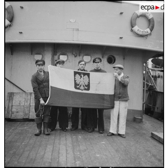 L'équipage du navire marchand polonais Korab II, au mouillage dans le port de Dunkerque, déploie le drapeau polonais.