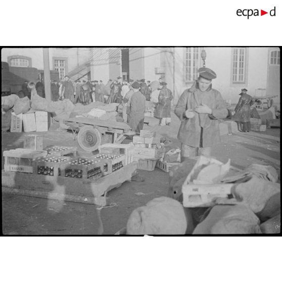 Marchandises et vivres stockés sur un quai devant les subsistances de la Marine.