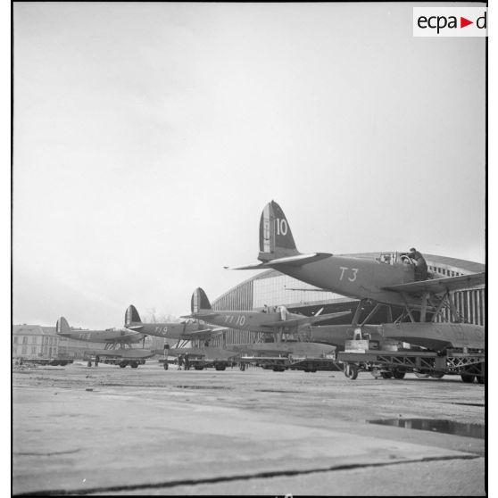 Des hydravions Latécoère 298 des escadrilles de torpillage T1 et T3 sont alignés devant des hangars de la base aéronautique navale de Cherbourg-Chantereyne.