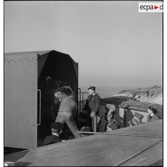 Lors de la visite de journalistes américains, des marins chargent un obus dans un canon de défense côtière dans la région de Brest.