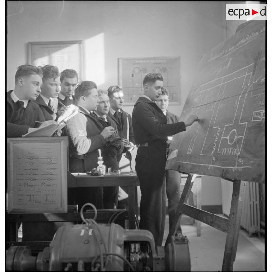 Elèves officiers de l'Ecole navale résolvant un exercice d'électricité (sous réserves) dans une salle de cours.