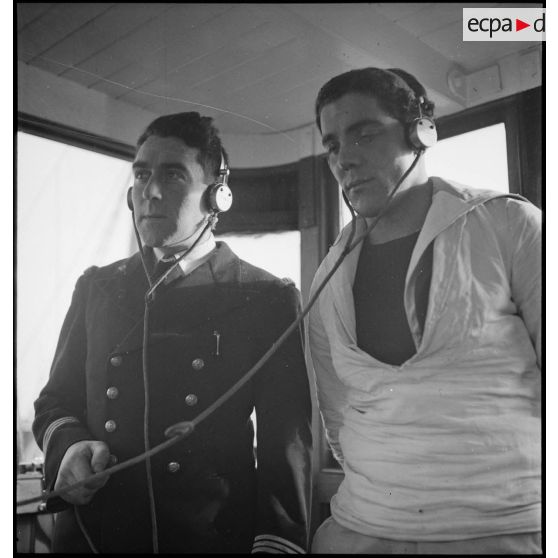 Le lieutenant de vaisseau commandant le patrouilleur La Lorientaise en compagnie d'un matelot, écouteurs sur les oreilles, à la passerelle de commandement.