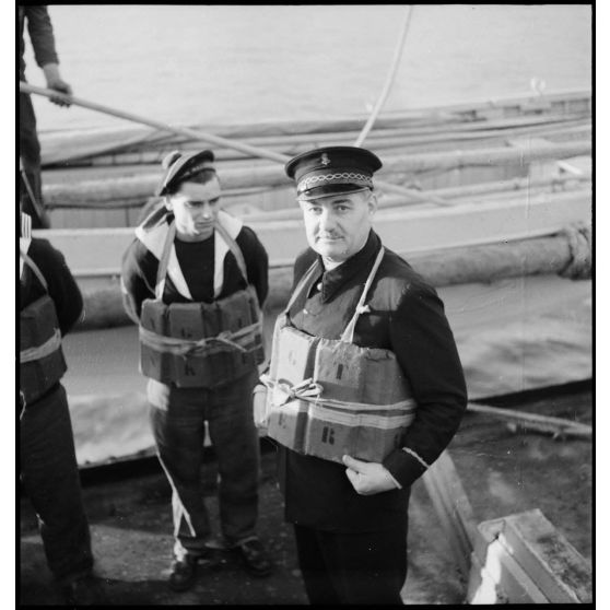 Membres d'équipage des marines nationale et marchande sur le pont, équipés de gilets de sauvetage, lors d'un exercice d'évacuation à bord du cargo réquisitionné Yang Tsé.