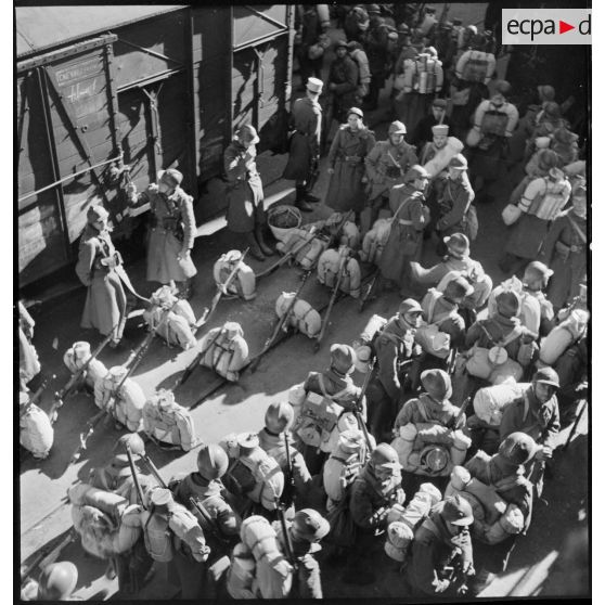 Des soldats d'unités de l'armée d'Afrique, débarqués sur un quai dans le port de Marseille, attendent leur embarquement à bord de wagons ferroviaires.