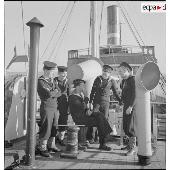 Des marins britanniques et français discutent sur le pont d'un cargo saisi par la Royal Navy et remis à la Marine nationale.