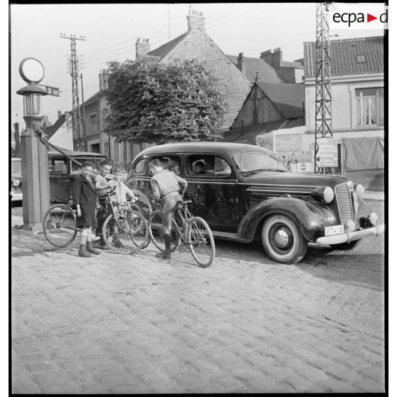 Des familles belges fuient l'invasion de leur pays par l'armée allemande à bord de véhicules et font le plein de carburant lors d'une halte à Boulogne-sur-Mer.