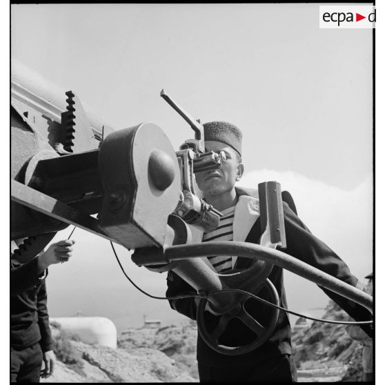 Un matelot canonnier algérien, dit Baharia, assure le pointage d'un canon de 75 mm modèle 1897, sur affût contre avions modèle 1916.