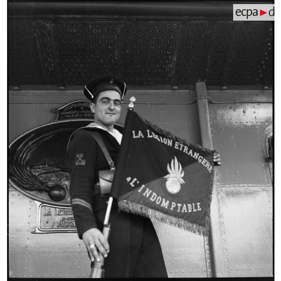 Le porte-fanion du contre-torpilleur L'Indomptable pose devant une plaque offerte par la Légion étrangère au navire.