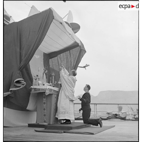 Elévation du calice par l'aumônier du cuirassé Dunkerque au cours d'une messe célébrée à bord du navire.