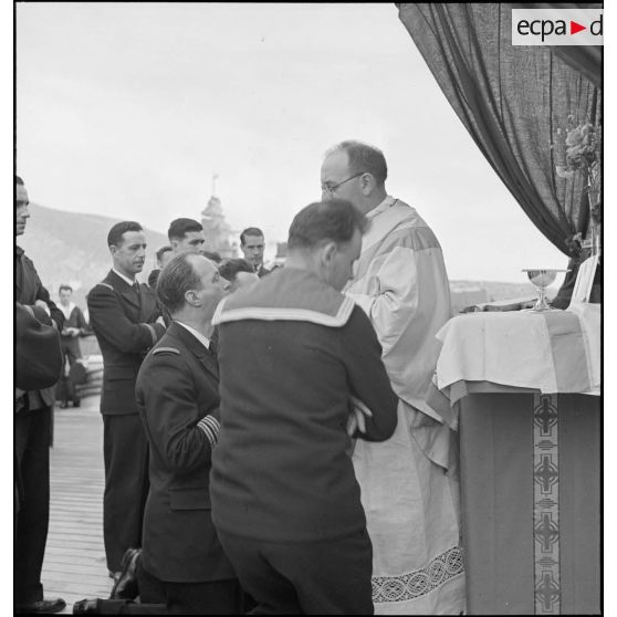 L'aumônier du cuirassé Dunkerque donne la communion à un capitaine de frégate lors d'une messe célébrée à bord du navire.